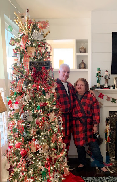 Living room decorated for Christmas with a Christmas tree, a couple wearing matching pajamas