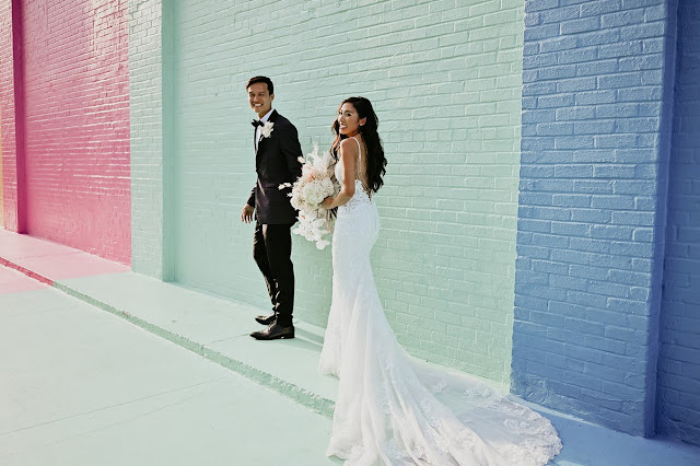 bride and groom in front of colorful wall