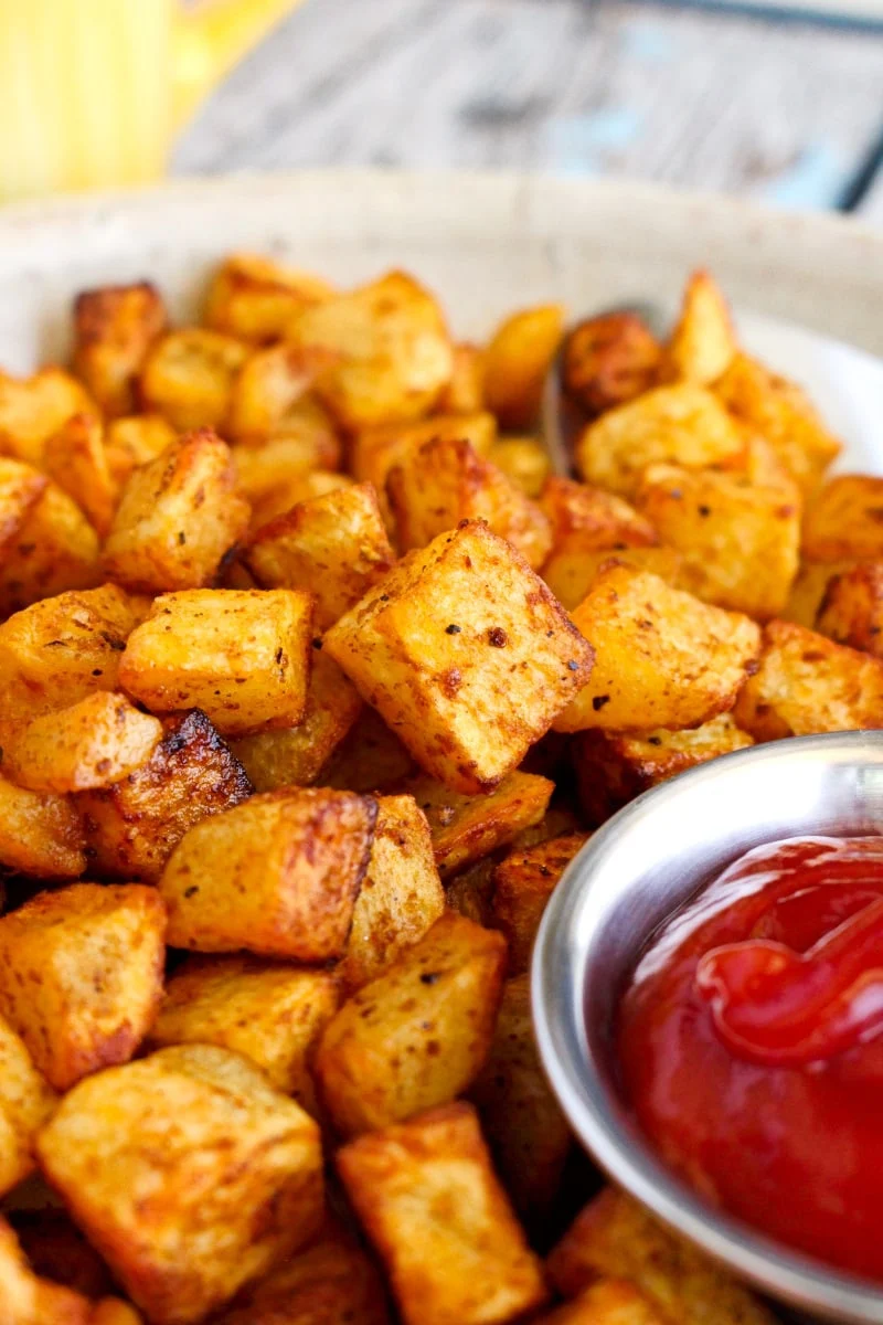 Air Fryer Breakfast Potatoes on a tan plate with a small silver ramekin of ketchup.