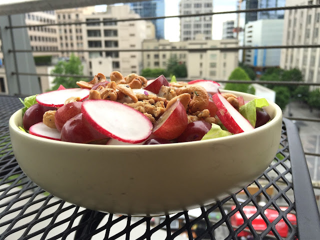 Salad on the table of a balcony displaying the roasted pepper cashews, radishes, sliced grapes, turkey and herb dressing in the afternoon light. 