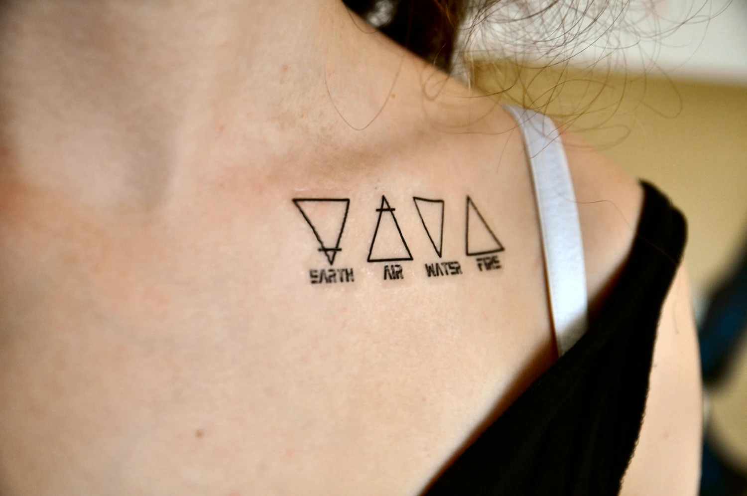 Mujer con tatuajes de triángulos en la clavícula