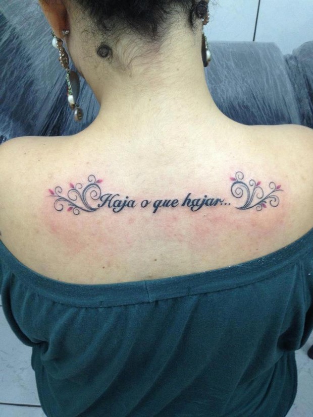 Mulher tatua "Haja o que hajar" nas costas