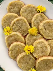 Finished cookies on a plate with dandelion flower heads.