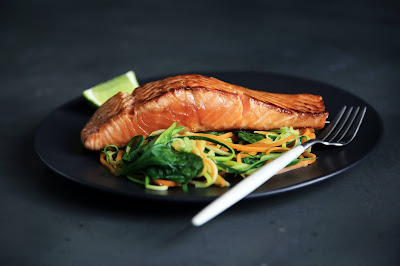 A plate with seared salmon, vegetables and a lemon wedge