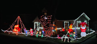 a brightly lit house with many Christmas inflatables includng the grinch