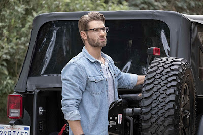 Mike Vogel stands outside his Jeep in dark rimmed glasses staring into the distance in Netflix's new movie Secret Obsession