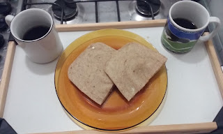 Numa bandeja, duas canecas de café e um prato com duas fatias de pão de aveia 