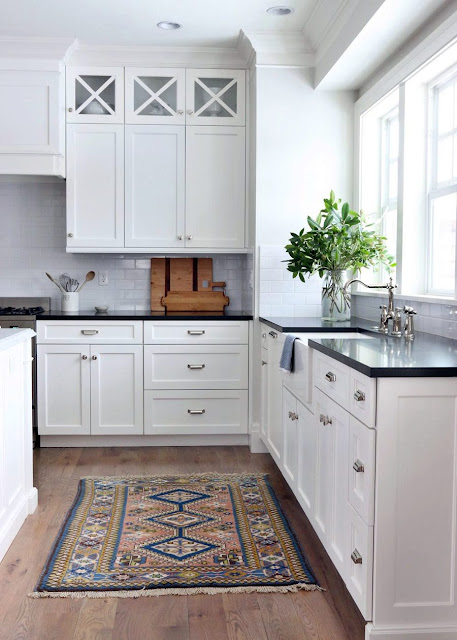 white kitchen cabinets with black countertops and white backsplash