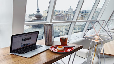 Pancake snack, beverage, books and laptop computer on a brown work station.