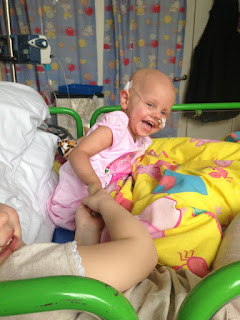 A little girl laughing whilst in her hospital bed