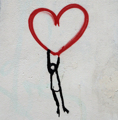 Street art of stick figure hanging onto bottom of red heart (Credit: Nick Fewings/Unsplash)