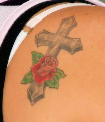 Cross and rose tattoo at the upper back of a woman Image Credit Link 