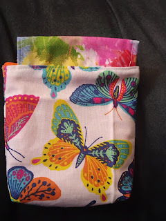 drawstring bag without drawstring, in butterfly print with abstract coordinating fabric casing. Casing is offcenter.