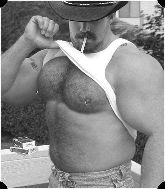 Black and white photo of a big beefy Cowboy smoking a cigar with a wife beater on