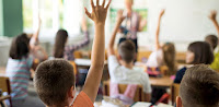 Elementary students with hands raised