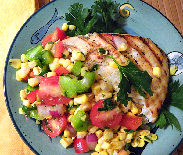 Closeup of Halibut and Corn Tomato Salad on Overflowing Plate