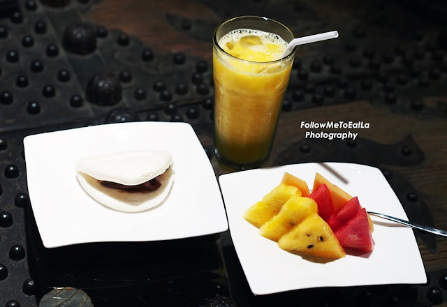 an appetizer of Roasted Duck with Butterfly Bun, seasonal fruits and a glass of juice.