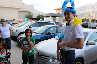 A balloon artist posing with a line of customers