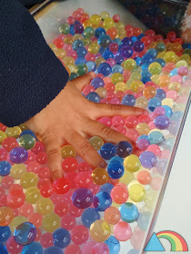 Mano sumergida en recipiente lleno de bolas de gel o water beads de colores