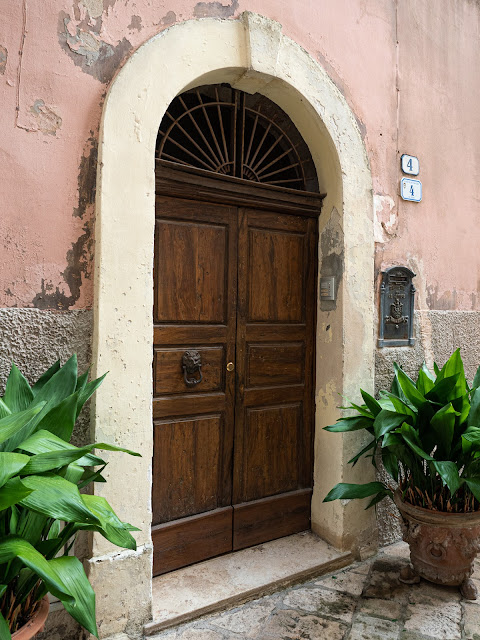 Puerta en Specchia rodeada de plantas con paredes desconchadas 