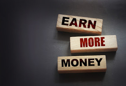 EARN MORE MONEY banner on wooden blocks.