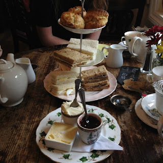 cake stand with sandwiches and scones and table laid