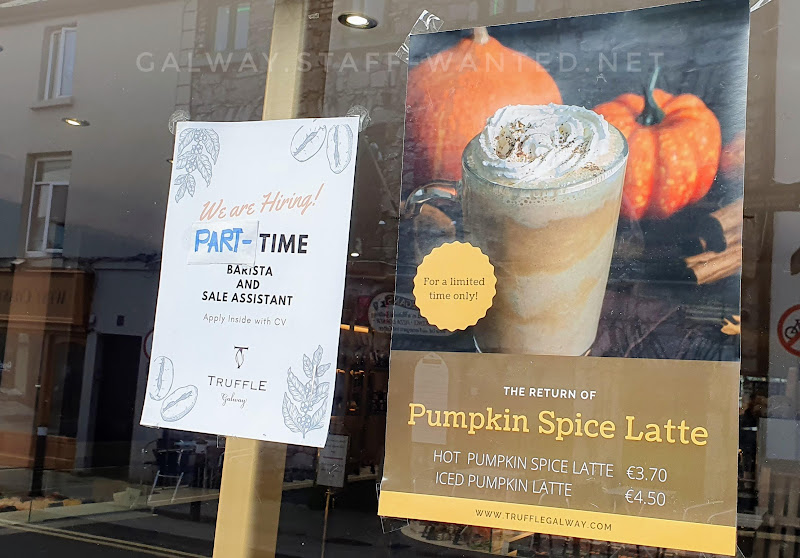 staff-wanted sign next to an oversized pumpkin spice latte poster in a gourmet chocolate shop in Galway city