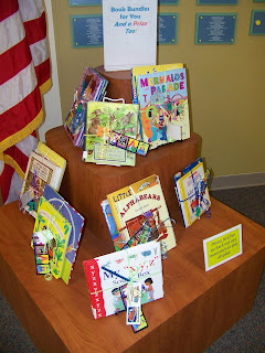 bundles of children's books tied together and displayed on tiered shelving