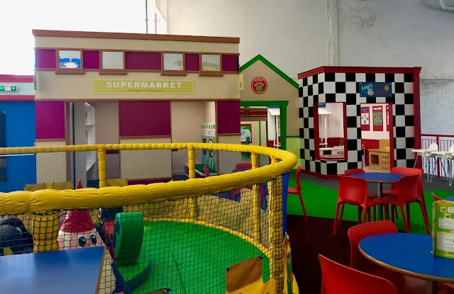 A view of the end of toddler soft play across to a pretend pizzeria, supermarket and post office