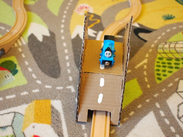 Train riding over DIY toy cardboard bridge