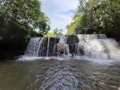 Visitante feliz disfrutando y refrescándose en una cascada en medio de la belleza natural.