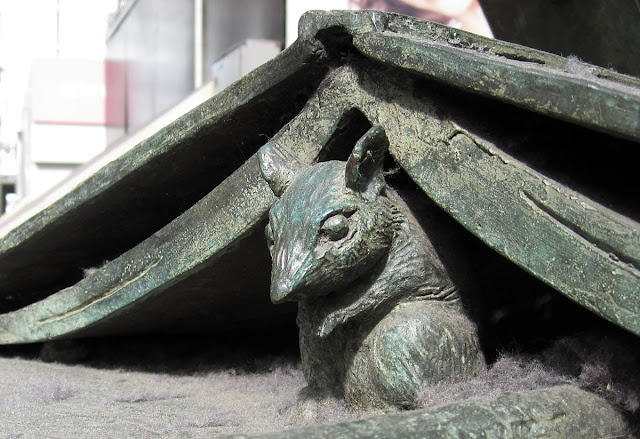 A mouse under a book at the back of the statue of Terence Tenison Cuneo by Philip Jackson in Waterloo Station, London. 19 April 2011.