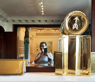 muler fazendo selfie no espelho com algumas instalações artísticas ao redor