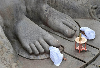 Two women worshipping the statue of Bahubali in Sravanabelagola