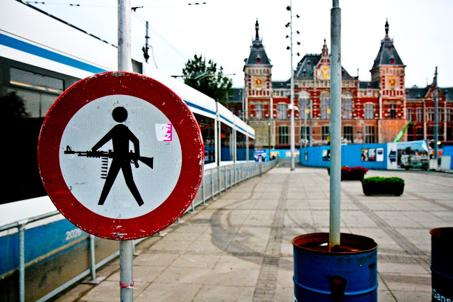 A train and a machine gun road sign outside of Amsterdam Centraal Station on a very cold morning.