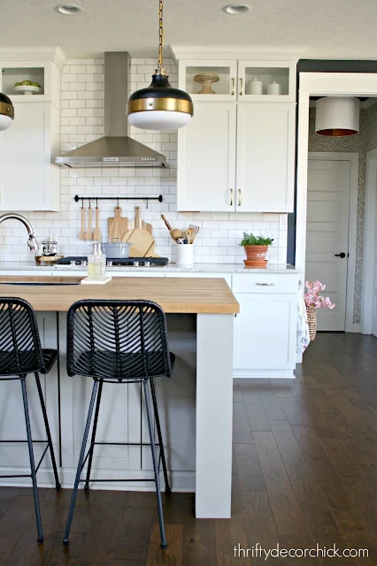 Light gray island, white kitchen cabinets, black stools