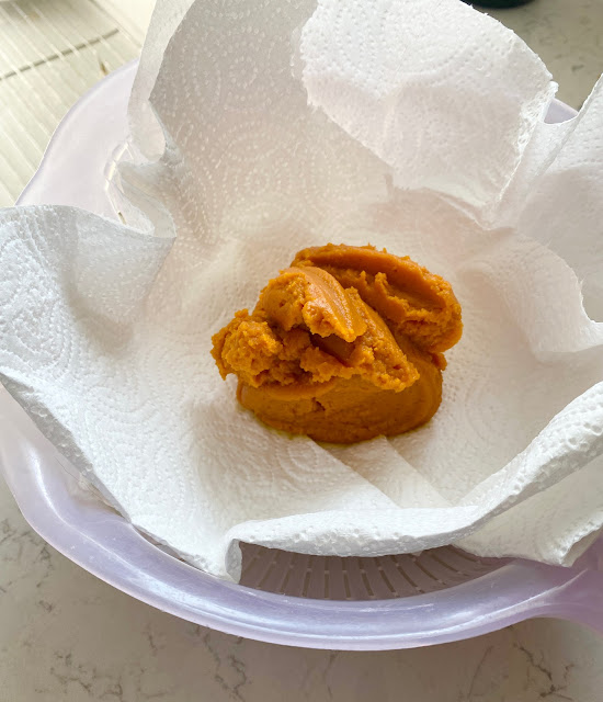 Pumpkin puree on paper towels in a strainer.