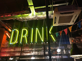 yellow neon sign saying DRINK