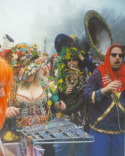 Costumed musicians in New Orleans French Quarter on a foggy Mardi Gras afternoon. Musician playing Glockenspiel at front left, Sousaphone at back right – Infrogmation (CC-by-SA-3.0)