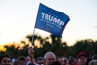 Trump supporter waves their flag while in line for the rally at USF in Tampa, FL.