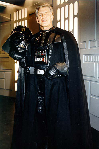 David Prowse posing on a STAR WARS set as Darth Vader.