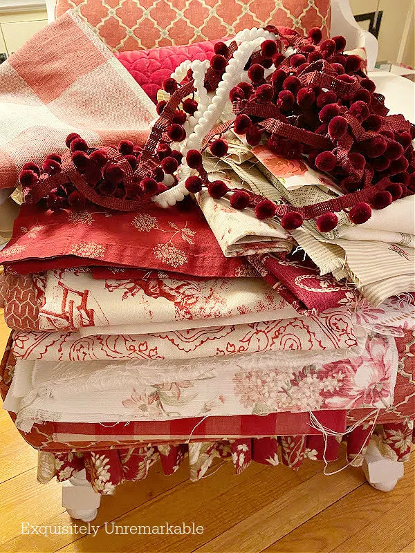 A pile of red and white fabrics and pom pom trim on top on a red chair
