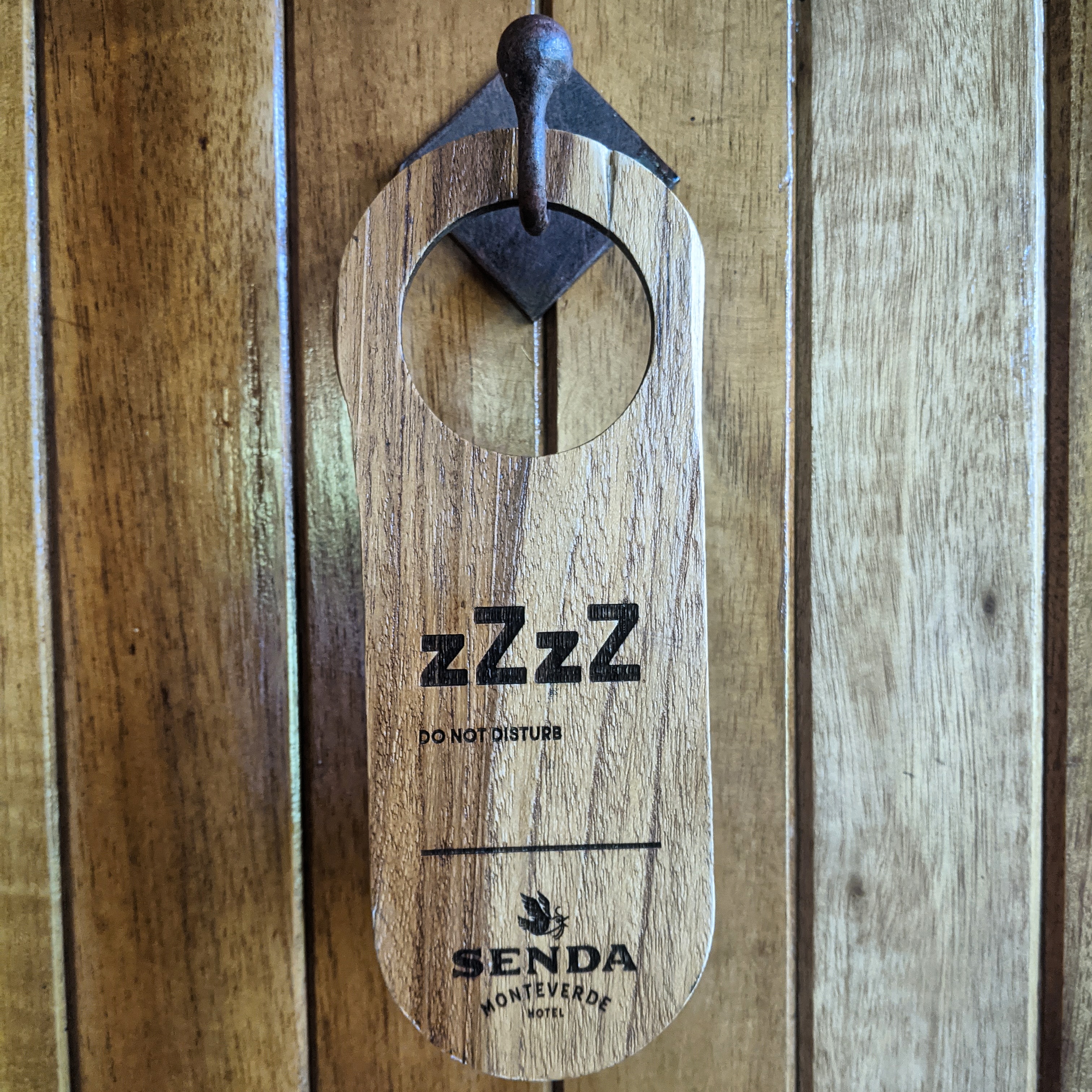 wooden do not disturb sign hanging on a door at senda moneverde hotel in costa rica