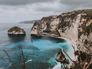 Vista do topo da falésia para a praia com formações rochosas