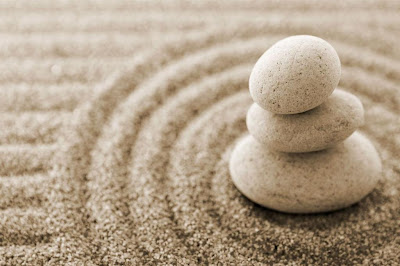 3 stones stacked, sitting in circles of sand - zen rock garden