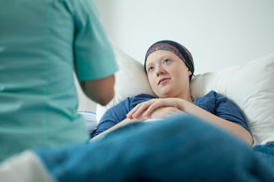 A photo of a cancer pating laying in bed. She is listening to her doctor. 