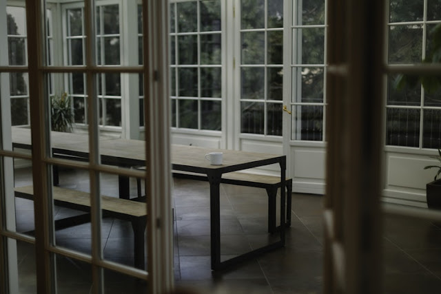 Inside of an orangery with a table and benches sat in the centre