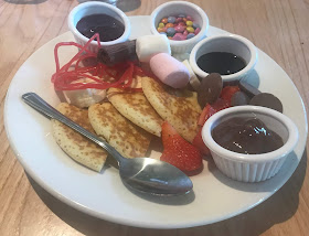 child make own pudding of pancakes, fruit, sauce and sweets