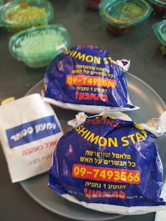 מנות שווארמה עטופות בשקית עם סלטים ברקע