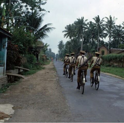 Polisi dari polda bali berpatroli melintasi jalan iman bonjol Denpasar menuju kuta dengan sepeda ontel. Di tahun 1979.